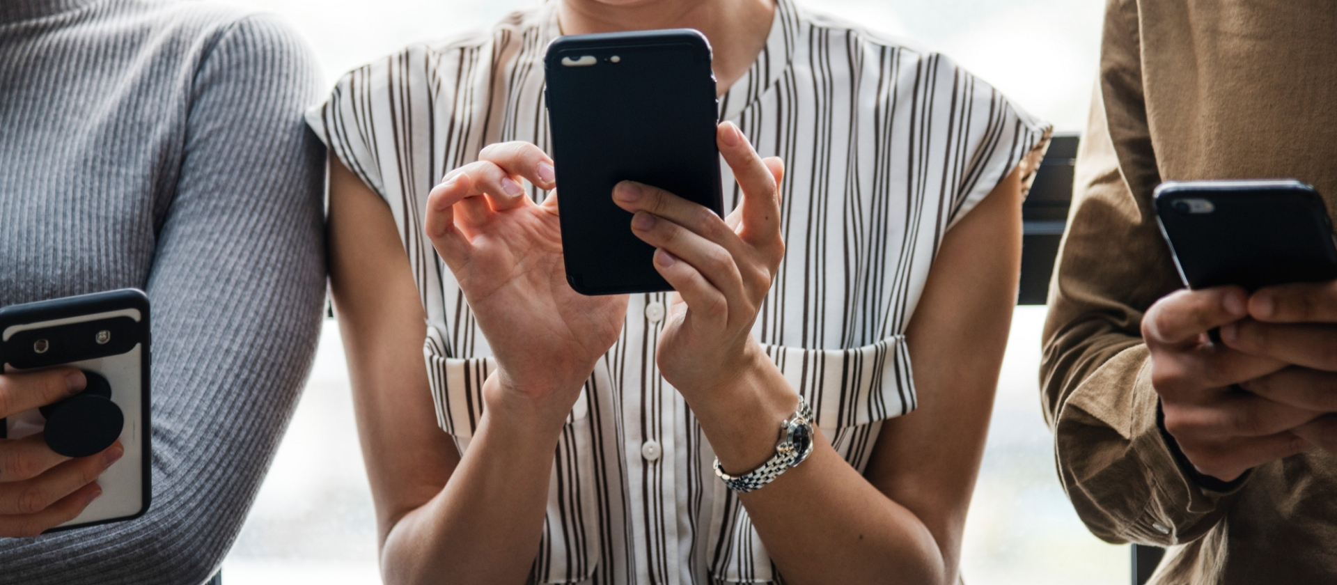 Two women and a man using their iphones